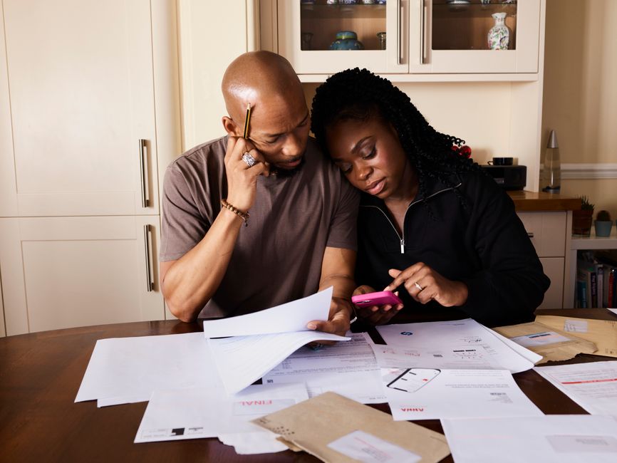 Couple examinant des documents financiers à table pour planifier un budget