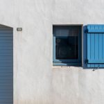 Facade blanche minimaliste avec volets bleus sur les fenetres