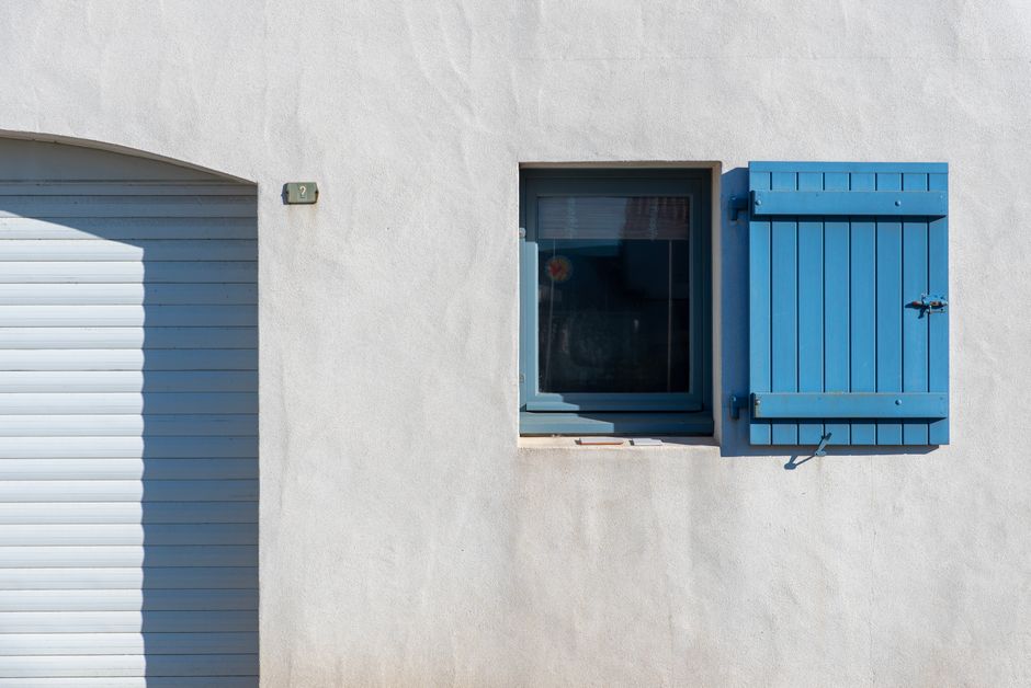 Facade blanche minimaliste avec volets bleus sur les fenetres