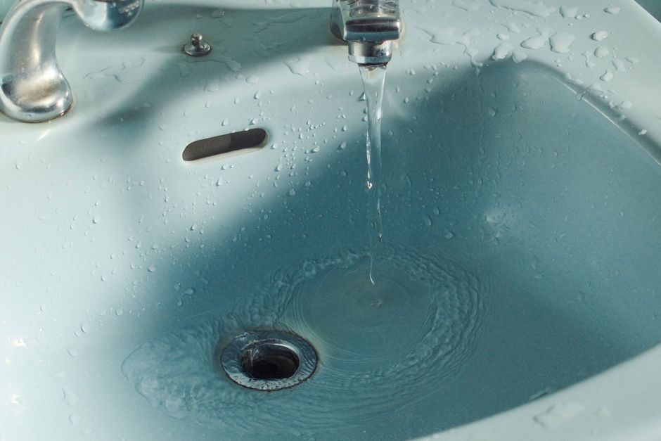 Lavabo avec bonde et trou de trop-plein visibles, eau qui s'écoule