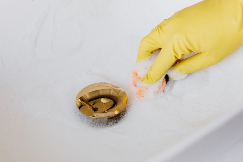 Main gantée nettoyant la bonde d'un lavabo