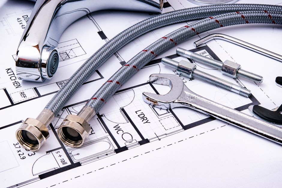 Outils de plomberie et flexibles posés sur un plan