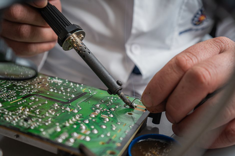 Technicien réparant une carte électronique à la soudure