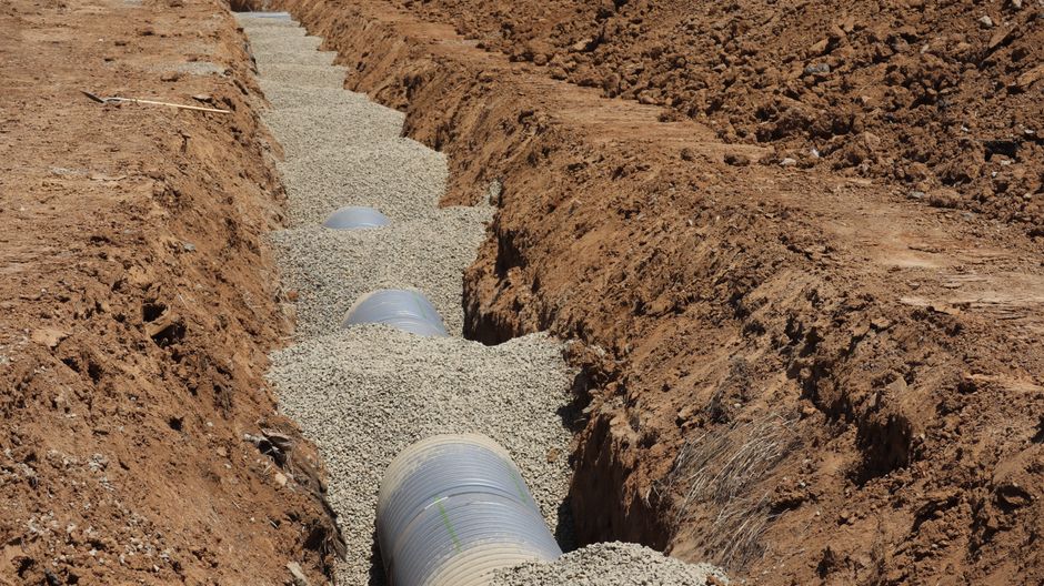 Tranchée de drainage avec tuyaux enterrés dans du gravier