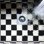 Évier à carreaux noirs et blancs avec de l'eau qui s'écoule vers la bonde