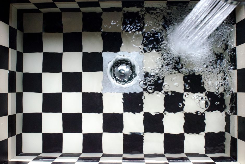 Évier à carreaux noirs et blancs avec de l'eau qui s'écoule vers la bonde